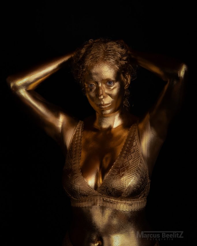Eine goldene Statue einer Frau mit hochgestecktem Haar und freiem Oberkörper.