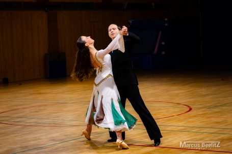 Tanzpaar in eleganter Pose auf einer Tanzfläche, die Bewegungen harmonisch synchronisiert.