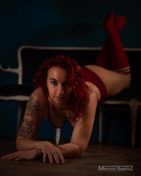 Frau mit roten Socken und tätowiertem Arm, die auf einer Couch posiert.