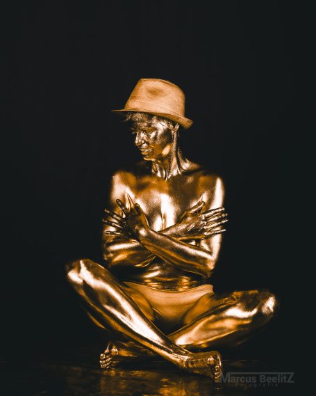 Goldene Frau eines mit Hut, die die Arme umschlungen hat.